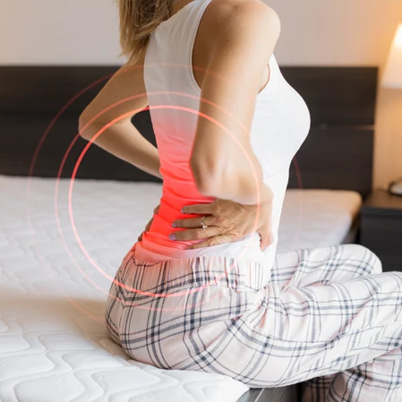 Woman With Back Pain Highlighted Red Sitting On Bed