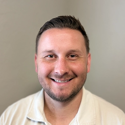 Chiropractor Joshua Harvey Smiling In Collared Shirt